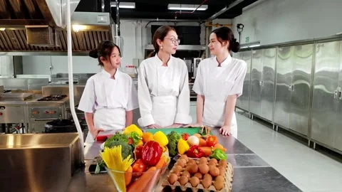 Chef instructor teaching two young culinary students in a commercial kitchen Video stock 320862639