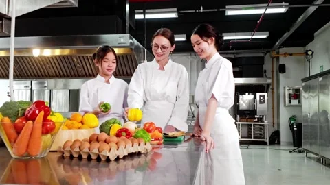 Chef instructor teaching two young culinary students in a commercial kitchen Video stock 320862696