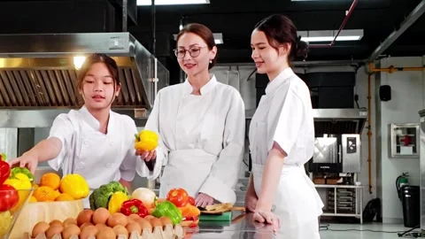 Chef instructor teaching two young culinary students in a commercial kitchen Video stock 323065899