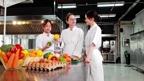 Chef instructor teaching two young culinary students in a commercial kitchen Видео 327122861