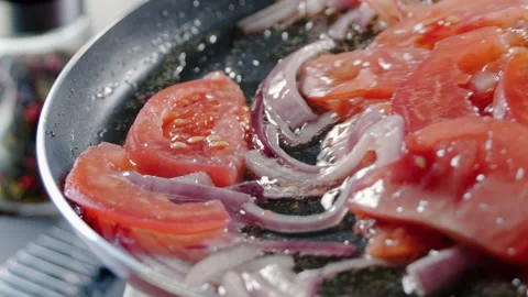 Chef interferes chopped tomatoe and onion slices by wooden spatula. Close-up of Stock Footage 151793992