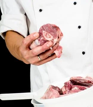 A chef in jacket, holding a lump of red meat Stock Photos