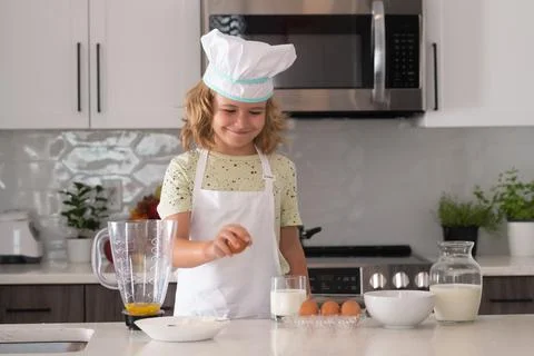 Chef kid boy baking on the kitchen. Child chef cook prepares food at kitchen Stock Photos
