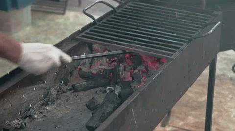 Chef kindles a fire and rake the charcoal on grill at street food festival Stock Footage 51170250