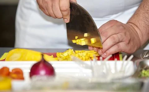 The chef in the kitchen cuts fresh pineapple for fruit salad with a knife. Stock Photos