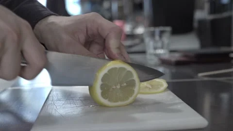 Chef in the kitchen cuts yellow lemon with sharp silver knife in half Stock Footage 160716053