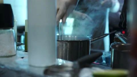 The chef in the kitchen, in a glove, pulls out the pasta with tongs and pans Stock Footage 141421390