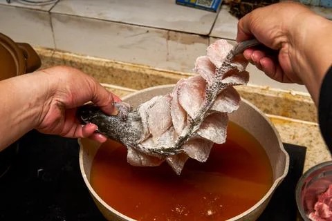 A chef in the kitchen is making fried fish, frying a whole fish Fotos de archivo