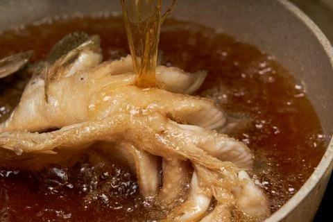 A chef in the kitchen is making fried fish, frying a whole fish Stockfoto's