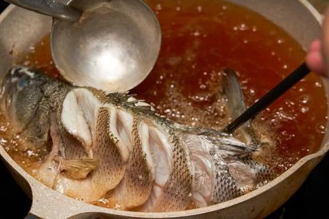 A chef in the kitchen is making fried fish, frying a whole fish Foto stock