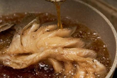 A chef in the kitchen is making fried fish, frying a whole fish Fotos de archivo