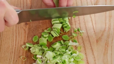 The chef in the kitchen prepares a healthy salad, chops leeks on a wooden board Stock Footage 265177147