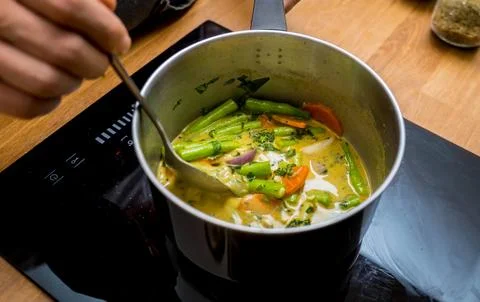 Chef at the kitchen preparing green curry with herbs and rice Stock Photos