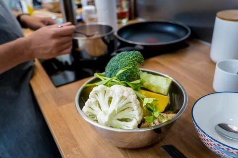 Chef at the kitchen preparing lentils soup with cauliflower and broccoli Stock Photos