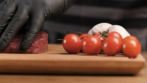 The chef in the kitchen in the restaurant cuts meat on a wooden board. On the Stock Footage 106931387