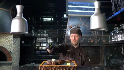 A chef in the kitchen of a restaurant serving his signature meat dish. Stock Footage 154893750