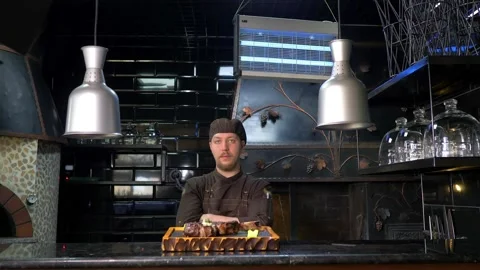 The chef is in the kitchen of the restaurant, serving steak with butter and Stock Footage 179696235