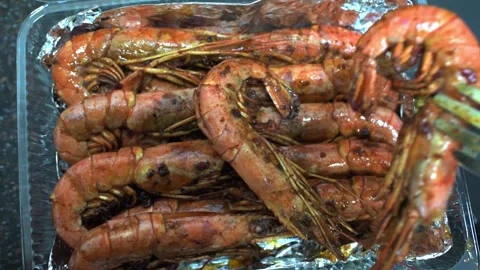 Chef with kitchen tongs puts fried shrimps in plastic box on foil. HD Stock Footage 141592352