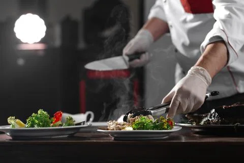 The chef in the kitchen unloading fish onto plates Stock Photos
