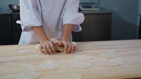 Chef kneading dough with flat circles on wooden table for Dumplings Stock Footage 299663785