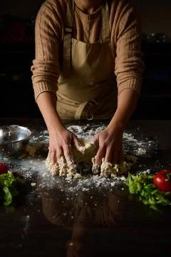Chef kneading dough on a kitchen counter with fresh ingredients nearby 스톡 사진