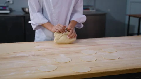Chef kneading dough with prepared flat circles on table Stock Footage 299663663