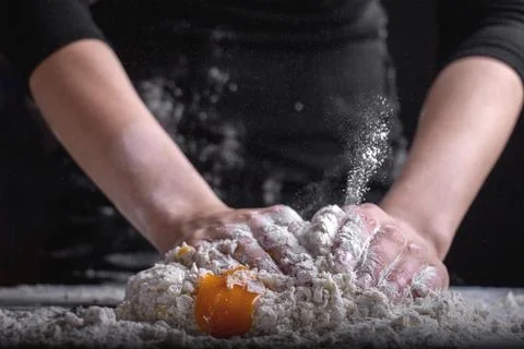 A chef is kneading dough using eggs, kitchen dark background Stock Photos