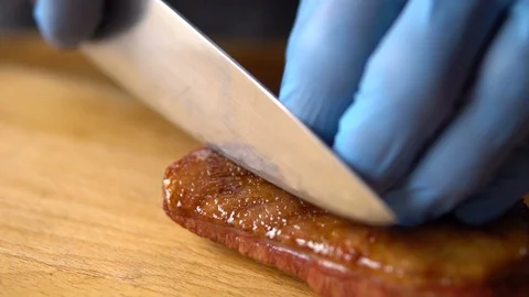 A chef with a large knife cuts grilled on charcoal duck breast Stock Footage 103204423
