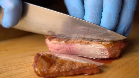 A chef with a large knife cuts grilled on charcoal duck breast Video stock 103310644