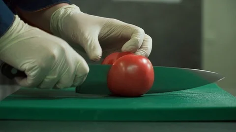 A chef with a large knife cuts a tomato. Cooking in the restaurant. Close-up Stock Footage 110799182