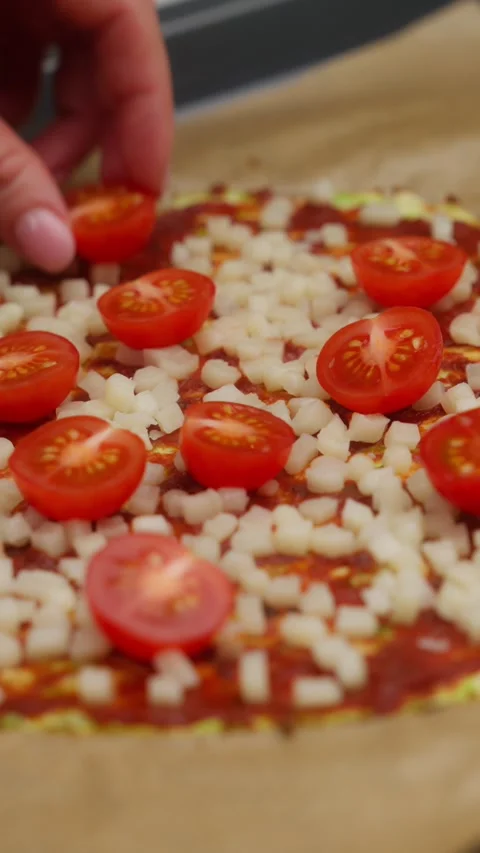 Chef lays cherry tomatoes on pizza dough with diced mozzarella Stock Footage 310951496