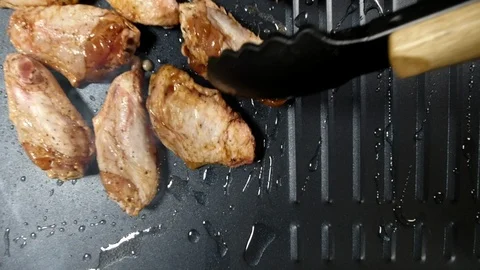 A chef lays chicken wings on the surface of a hot grill. Stock Footage 121762380