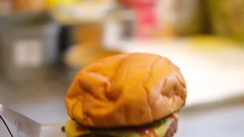 Chef Lifting Finished Cheeseburger From Grill To Wrapping Paper For Service In Stockbeeldmateriaal 332683424