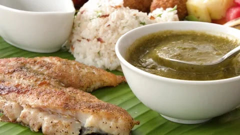 Chef lifting spoon of green soup over grilled fish fillet with rice and fru.. 库存影片 333617298