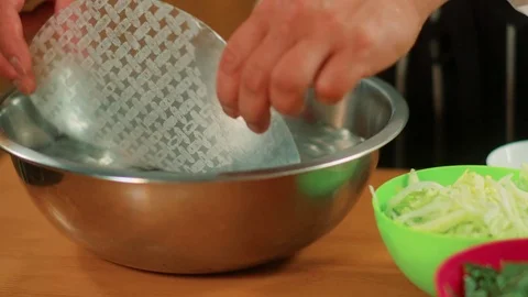 Chef lifting spring roll wrapper from bowl with water Stock Footage 83325493