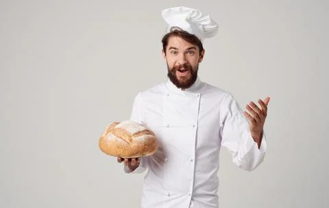 Chef with a loaf of bread in his hands on a light background and professional Stock Photos