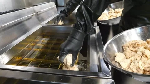 Chef lowering battered chicken into deep fryer for Korean fried chicken, close u Video stock 343028654
