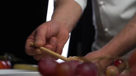 The chef lowers a wooden spoon into bright yellow honey, which slowly flows back Stock Footage 144044341