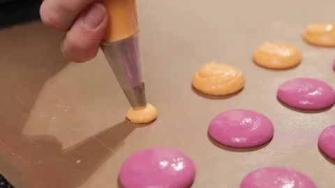 Chef make of a pink and orange macaroons, pour the filling on the baking paper. Stock Footage 148659687