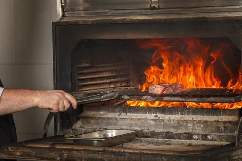 Chef makes beef steak on open fire in restaurant Foto stock