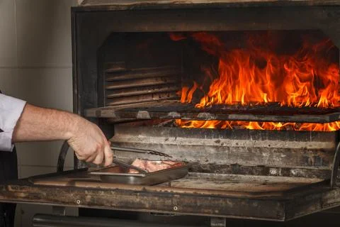Chef makes beef steak on open fire in restaurant 스톡 사진