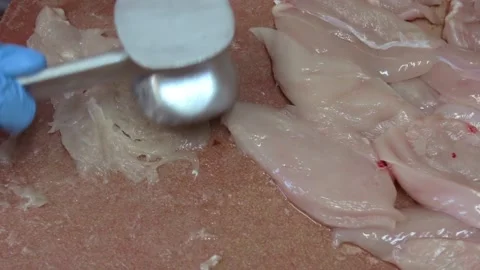 Chef makes chops from chicken breasts by steel kitchen hammer on a wooden boa Stock Footage 143778441