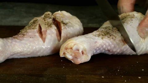 Chef makes cuts on raw chicken legs with kitchen knife. Stock Footage