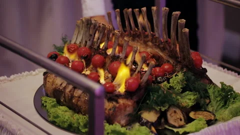 The chef makes the dining hall, lamb on a platter. Sets fire to cook rack of Stock Footage 104074584