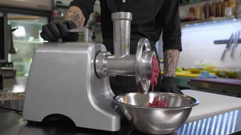 The chef makes minced meat in a meat grinder in the kitchen of the restaurant. Stock Footage 345132248