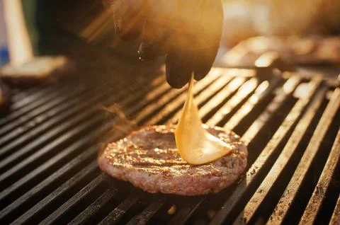 Chef making beef burger with cheese on open kitchen. Stock Photos