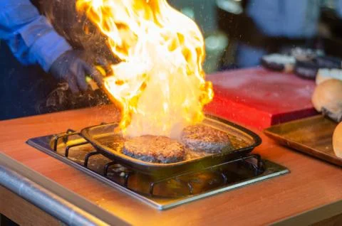 Chef making beef burger with cheese outdoor on open kitchen. Fast food. Stock Photos