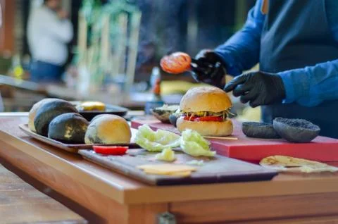 Chef making beef burger with cheese outdoor on open kitchen. Fast food. Stock Photos