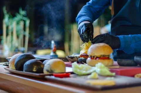 Chef making beef burger with cheese outdoor on open kitchen. Fast food. Stock Photos