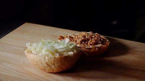 Chef making burger. frying the bun on the grill, putting sliced pickled cucumber Stock Footage 97576108